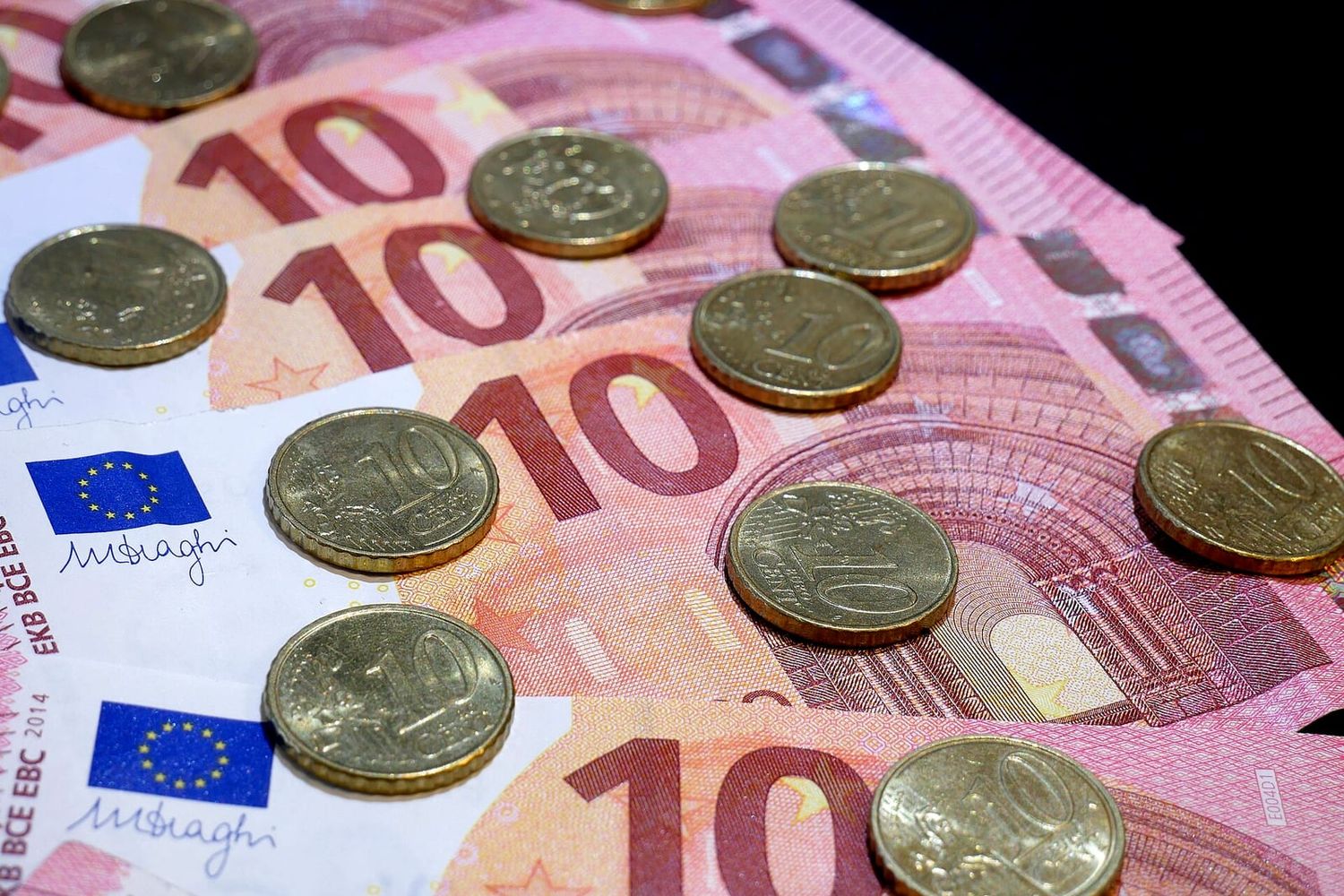 Aufgefächerte Zehn-Euro-Scheine mit darauf verteilten Zehn-Cent-Münzen
